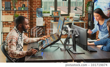 Graphic designer working on photo retouching with editing software, using tablet and stylus to create digital art in creative agency studio. Artist creating picture edit with color grading. 101719874