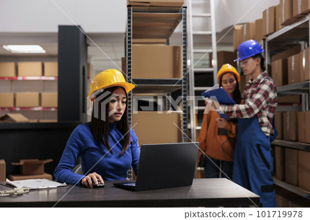 Retail storehouse young asian employee processing online order on laptop. Warehouse worker checking goods inventory automation system on computer in freight parcels storage room 101719978