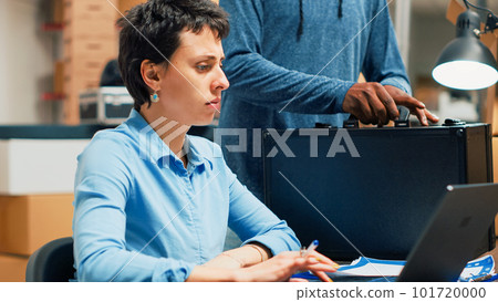 Business partners looking at products in boxes before shipping order to clients, doing quality control. Two people working on supply chain logistics and distribution management on pc. Handheld shot. 101720000