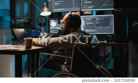 System admin using terminal window on laptop to program new code, dealing with physical impairment. Male web developer in wheelchair coding firewall security or html script. Tripod shot. 101720039