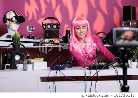 Asian influencer filming vlog with professional equipment talking with channel subscribers discussing lifestyle advice. Vlogger with pink hair recording vlog posting on social media, live streaming 101720112