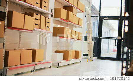 Multiple carton boxes placed on shelves in warehouse, storage room space filled with products and merchandise in packages. Stock distribution and shipment in empty industrial depot. Handheld shot. 101720145