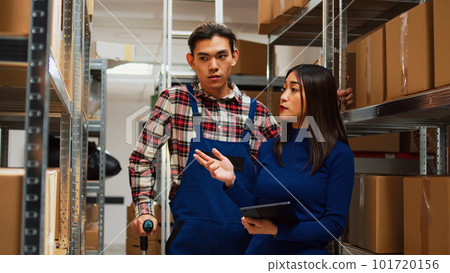 Asian adult walking in crutches talking to woman, planning stock logistics for order management in warehouse. Business owner working with tablet to analyze products with young man. Asian adult walking in crutches talking to woman, planning stock logistics for order management in warehouse. Business owner working with tablet to analyze products with young man. 101720156