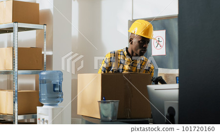 Storage room employees checking boxes of goods in warehouse, using computer to work on quality control and logistics. Young people carrying merchandise in packages, stock distribution. 101720160
