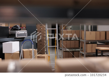 Selective focus of tall metal shelves filled with various carton boxes and containers ready for delivery, empty industrial warehouse. Storehouse building used for storage and distribution centers Selective focus of tall metal shelves filled with various carton boxes and containers ready for delivery, empty industrial warehouse. Storehouse building used for storage and distribution centers 101720234