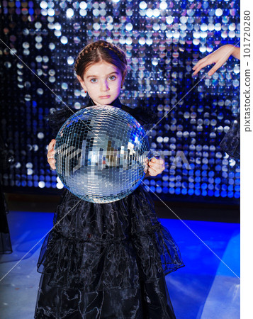 little girl with pigtail with mirror ball in a black long dress. shiny wall 101720280