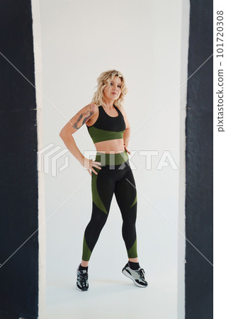 an attractive blonde in a black and green tracksuit poses in the photo studio  101720308