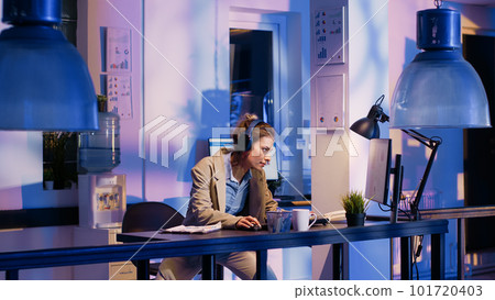 Cheerful employee working on research with headset, listening to music while typing economy data on computer. Young adult planning investment before deadline, wearing headphones. Cheerful employee working on research with headset, listening to music while typing economy data on computer. Young adult planning investment before deadline, wearing headphones. 101720403