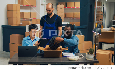 Business owners checking quality of supplies before packing them in carton boxes, putting merchandise for shipping. People working together on warehouse shipment, retail distribution. 101720404