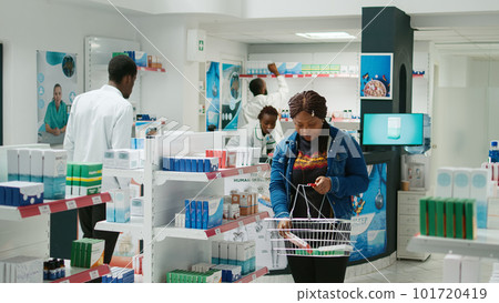 Female client taking boxes of pills and vitamins from drugstore, buying medicaments for healthcare. Young woman checking supplements and pharmaceutical products, medical store. Female client taking boxes of pills and vitamins from drugstore, buying medicaments for healthcare. Young woman checking supplements and pharmaceutical products, medical store. 101720419
