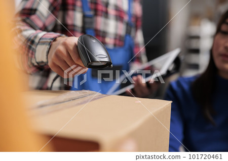 Retail storehouse employees doing inventory management while scanning packages. Postal service warehouse manager holding barcode scanner and digital tablet in arm close up Retail storehouse employees doing inventory management while scanning packages. Postal service warehouse manager holding barcode scanner and digital tablet in arm close up 101720461