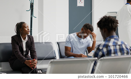 Group of patients sitting in hospital waiting room and reading medical insurance fliers, waiting for physician. People at health center having checkup visit appointments to cure disease. Group of patients sitting in hospital waiting room and reading medical insurance fliers, waiting for physician. People at health center having checkup visit appointments to cure disease. 101720466