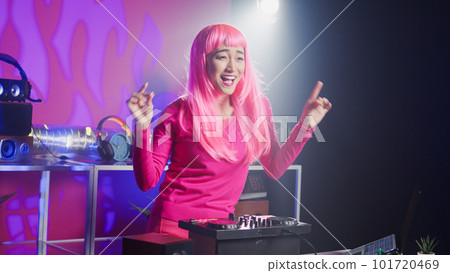 Dj artist using professional mixer console in nightclub, mixing techno sound creating unique remix for fans. Asian performer with pink hair playing musical album, performing eletronic music 101720469