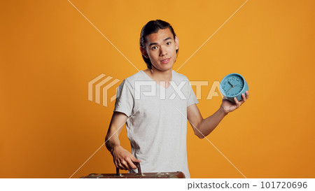 Male person carrying suitcase and checking time on clock, preparing to leave with briefcase and running late. Stressed young man being in a hurry and looking at watch, holding bag. Male person carrying suitcase and checking time on clock, preparing to leave with briefcase and running late. Stressed young man being in a hurry and looking at watch, holding bag. 101720696