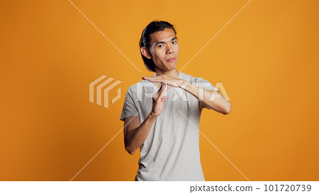 Young adult doing t shape symbol on camera, showing break or pause sign for denial and refusal. Asian casual guy expressing rejection and asking for half time, body language concept. 101720739