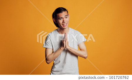 Positive young adult holding hands in prayer and acting spiritual, being religious and confident in studio. Happy cheerful man praying and asking to fulfill wish, showing belief and confidence. Positive young adult holding hands in prayer and acting spiritual, being religious and confident in studio. Happy cheerful man praying and asking to fulfill wish, showing belief and confidence. 101720762