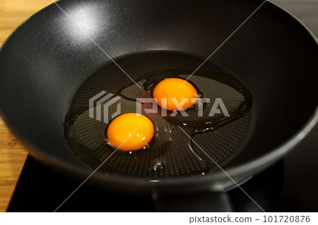 Two raw eggs with yellow yolks on the black frying pan ready to cook. Delicious healthy simple breakfast meal. Traditional homemade quick breakfast. International cuisine food. Top view. Two raw eggs with yellow yolks on the black frying pan ready to cook. Delicious healthy simple breakfast meal. Traditional homemade quick breakfast. International cuisine food. Top view. 101720876