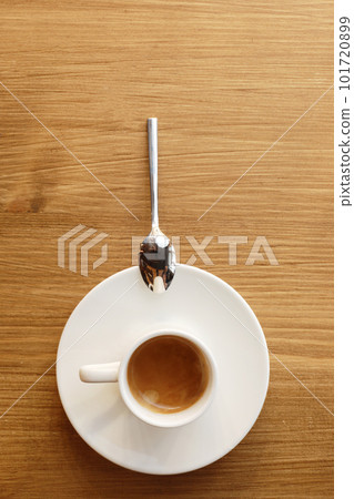 Top view of white porcelain cup with plate and metal spoon of hot coffee with milk on wooden table background. Top view of white porcelain cup with plate and metal spoon of hot coffee with milk on wooden table background. 101720899