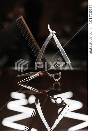 Barber shop equipment sets on dark glass background. Comb, steel scissor and vintage straight razor in air. Professional hairdressing tools. Beauty industry, art, self-care concept. Place for text. 101720923