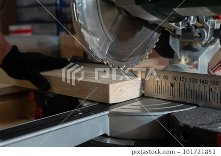 The master cuts the board with a circular saw in the workshop. Close-up of a carpenter's male hands at work. The master cuts the board with a circular saw in the workshop. Close-up of a carpenter's male hands at work. 101721851