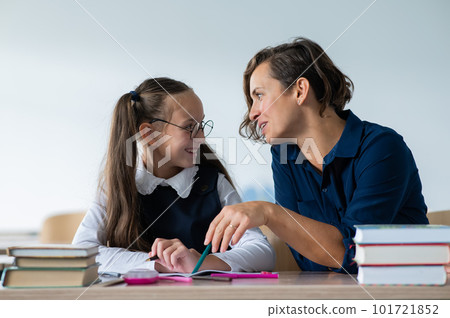 The teacher explains the task to the schoolgirl in the classroom. 101721852