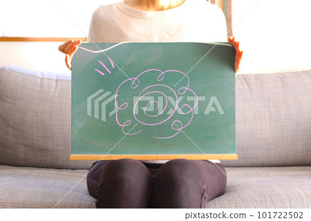A woman holding a blackboard with a flower circle mark 101722502
