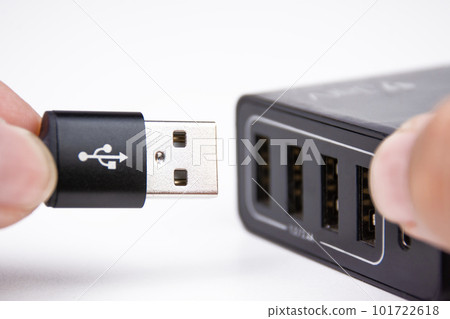 USB A charging cable in hand is plugging into a multi port mobile phone charger. 101722618