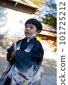A 5-year-old child wearing a kimono and visiting the Shichi-go-san Shrine is walking through the grounds of a shrine wearing a chin mask. 101725212