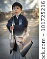 A 5-year-old child wearing a kimono and visiting the Shichi-go-san shrine stands in the precincts of a shrine with a chin mask. 101725216