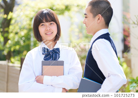 在明亮的植物、校服、學校生活前交談的初中男孩和女孩 在明亮的植物、校服、學校生活前交談的初中男孩和女孩 101725273
