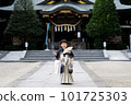 A 5-year-old child in Japanese clothes who came to visit the shrine for Shichi-Go-San festival spreads a folding fan in front of her chest and stands smiling with the main building of a shrine in the background. 101725303