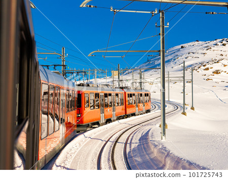 Red train running on rack railway through snowy Swiss Alps 101725743