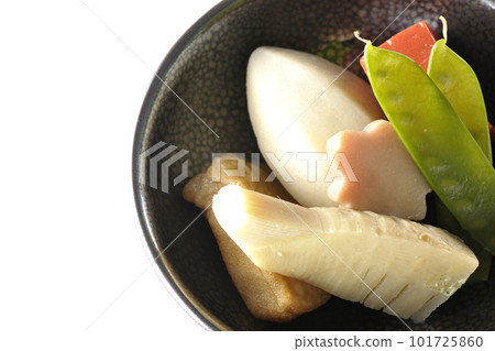 A bird's-eye view of a simmered dish containing bamboo shoots, taro, namafu, snow peas, etc. against a white background 101725860