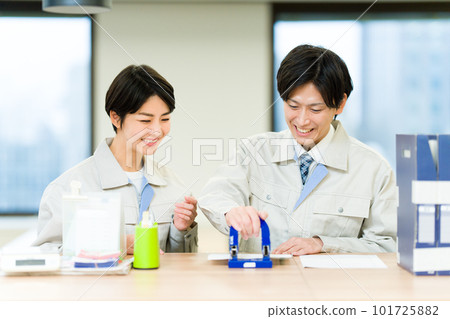 Men and women wearing work clothes punching holes 101725882