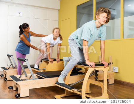 Teen boy and girl in sportswear, pilates training on exercise machine Teen boy and girl in sportswear, pilates training on exercise machine 101726064