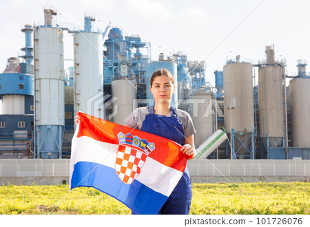 near backdrop of factory located outside city,stands balanced girl in overalls with flag of Croatia 101726076