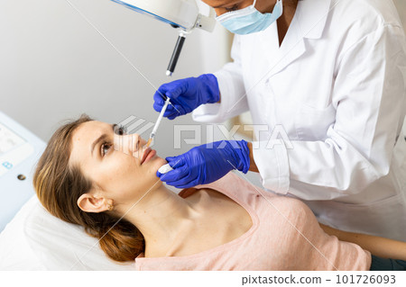 Woman receiving cosmetic facial injection at clinic 101726093