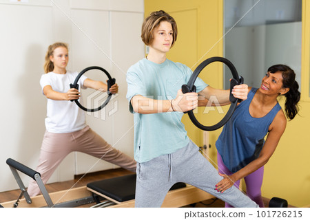 Young boy and girl with pilates trainer in gym 101726215