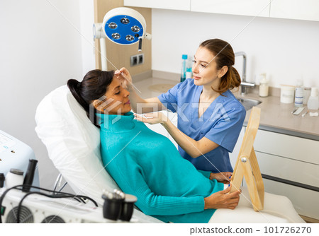 Female beauty doctor looking at woman's face during examination 101726270