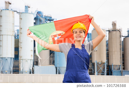 Happy woman waving flag of Portugal against the background of modern factory Happy woman waving flag of Portugal against the background of modern factory 101726388
