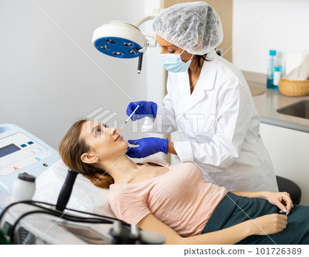 Woman receiving cosmetic facial injection at clinic 101726389