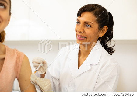 Doctor vaccinates woman at vaccination center Doctor vaccinates woman at vaccination center 101726450