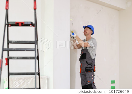 Smiling worker in uniform coveralls makes repairs in flat Smiling worker in uniform coveralls makes repairs in flat 101726649
