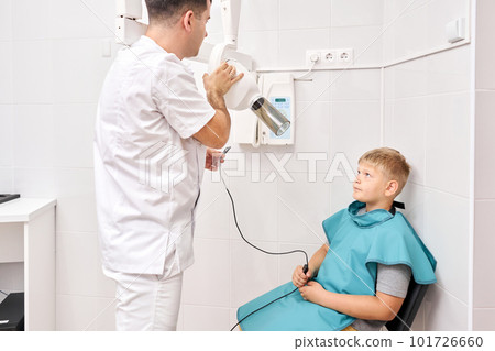 Radiographer taking teeth radiography to a boy using digital x-ray machine in pediatric dental clinic. Dentist prepares boy for tooth x-ray image in dental clinic. 101726660
