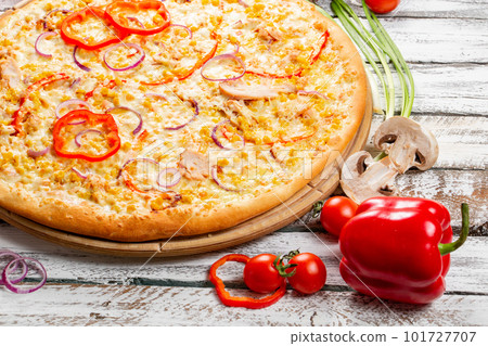 Pizza with chicken, paprika and corn. Italian kitchen and cooking concept. Chief with a pizza cutter cutting pizza to pieces at Neapolitan pizzeria. 101727707