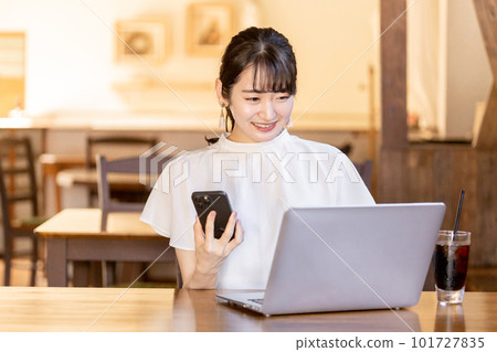 Asian business woman doing remote work/telework using a computer/smartphone at a cafe or coffee shop 101727835