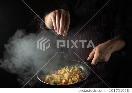 Cooking fresh vegetables and pasta. The chef adds salt to a steaming hot pan. Thai Restaurant Cuisine Cooking fresh vegetables and pasta. The chef adds salt to a steaming hot pan. Thai Restaurant Cuisine 101731038