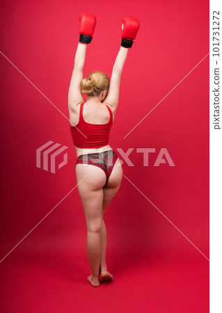 Seductive young and fit female fighter posing in gloves in studio 101731272