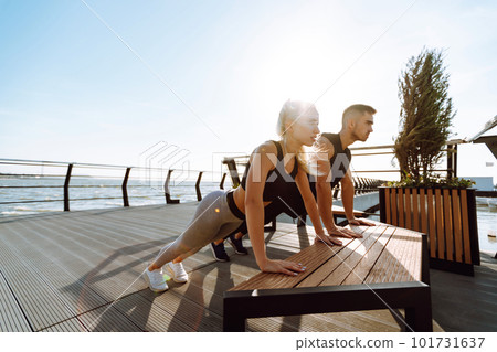 Romantic couple doing sport together at the beach pier. Two sporty athletes doing warming-up excersises. 101731637
