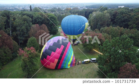 Balloon Festival. Inflating and lifting big balloon aerostat. Several balloons inflate and raise in meadow in forest. Entertainment rest, recreation, travelling Balloon Festival. Inflating and lifting big balloon aerostat. Several balloons inflate and raise in meadow in forest. Entertainment rest, recreation, travelling 101731739